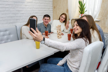 Group of people playing tower in cafe and making selfie