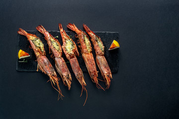dishes with langoustines, in a plate on a black background. view from above. copyspace.