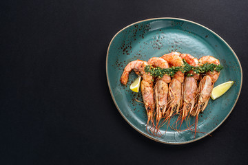 dishes with langoustines, in a plate on a black background. view from above. copyspace.
