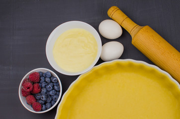 shortbread dough for baking quiche tart and ingredients in baking form with berries. baking concept