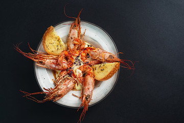 dishes with langoustines, in a plate on a black background. view from above. copyspace.