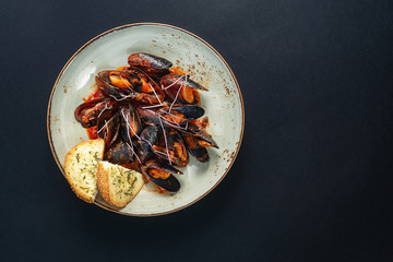 dishes with mussels in a plate on a black background. view from above. copyspace. seafood