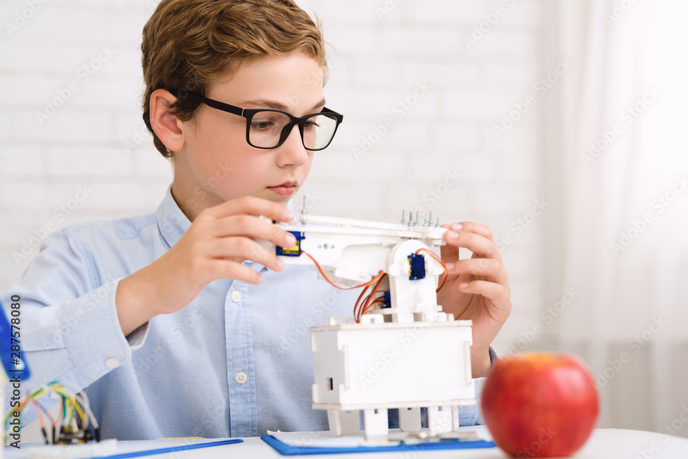 Poster Smart schoolboy constructing electronic robot at stem class