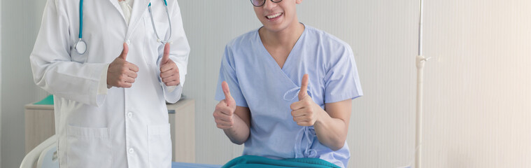 Young Asian beautiful doctor and Asian teenage patient showing thumbs up with smiley face in the...
