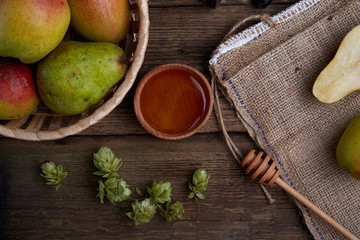 Flat lay with a pears with nuts on dark wooden background. With hops and honey.