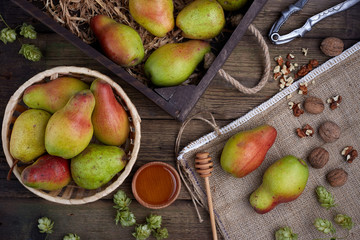 Flat lay with a pears with nuts on dark wooden background. With hops and honey.