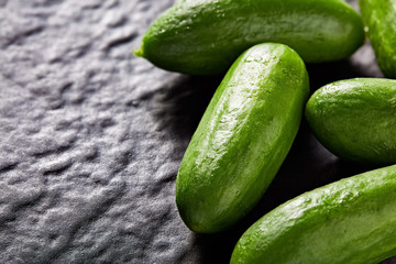 Heap of cucumbers on black textured stone background with copy space. Close up macro view.