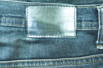 Leather label sewed on jeans. leather label on worn blue denim with orange seams, good for background.