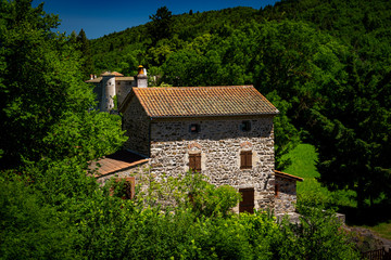 Obraz premium Two french stone buildings in heavy woodland
