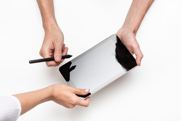 Close up top view of male and female hands holding tablet. Man signs contract with a pen using...