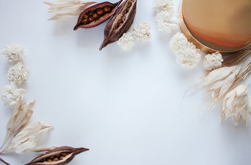 Gold jar of cream and dry flowers on white background, top view closeup