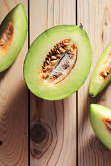Halve melon and slices on wooden table. Top view