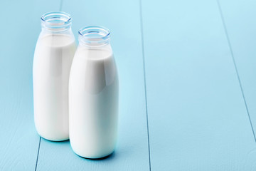 Two bottles of milk on blue wooden retro table. Close up view.
