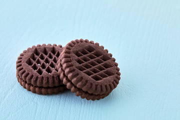 Two chocolate cream filled biscuits on blue wooden table. Close up macro view.