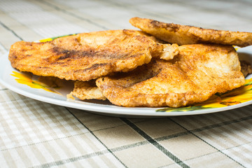 Fried tilapia fish fillets in plate on the kitchen table.