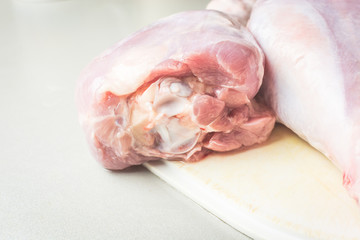 Thawed raw turkey legs on white cutting board for cooking.