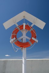 Orange lifebuoy hang on metal pole tied with ropes
