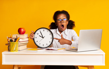 Elementary Student Girl Pointing Finger At Clock Sitting At Laptop