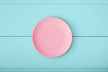 Pink empty plate on turquise wooden table. Top down view with copy space.