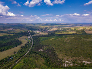 Aerial view of a provincial road passing through a forest and green lands