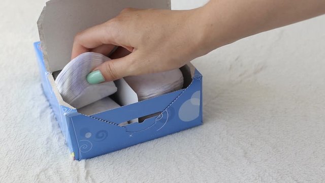 girl opens a box with daily sanitary pads and takes one, close-up, sanitary napkin