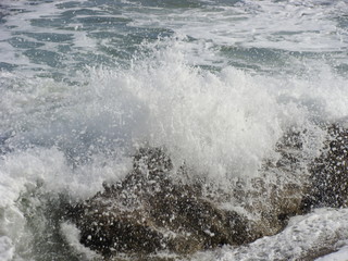 Wave breaking on the seashore with sea foam and forming a big spray.