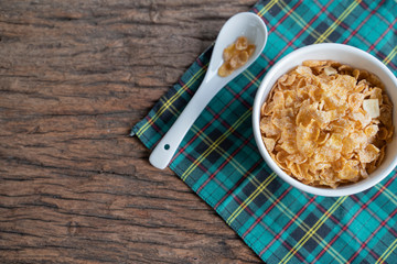 Cornflakes on wooden table at morning.