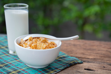 Cornflakes and milk on wooden table at morning.