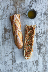 Sándwich de chapata con pesto, hierbas, jamón, salami, salchichas, mozzarella y espinacas sobre fondo de madera gris.