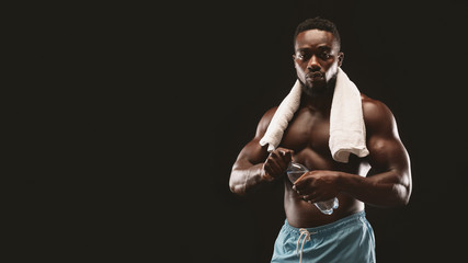 Handsome black bodybuilder drinking water during exercising