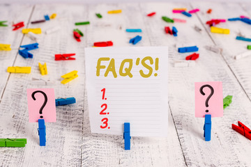 Text sign showing Faq S. Business photo showcasing list of questions and answers relating to particular subject Scribbled and crumbling sheet with paper clips placed on the wooden table