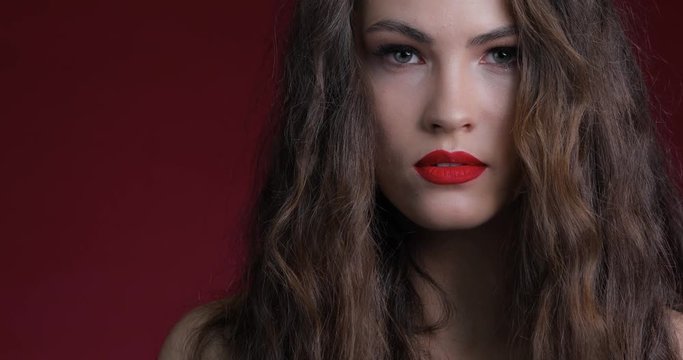 Sensual beautiful woman with long curly hair. Red manicure, red lips.