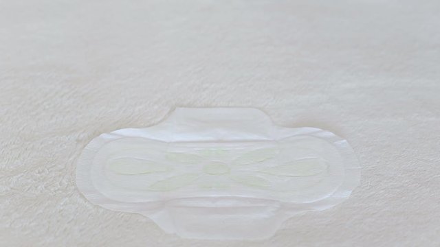The girl checks with a napkin the sanitary pad for menstruation for dryness and protection, feminine pads