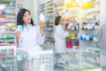 Two Asian pharmacists are inspecting and sorting medicine on the shelves in pharmacies. Health business, Health care and medical concepts.