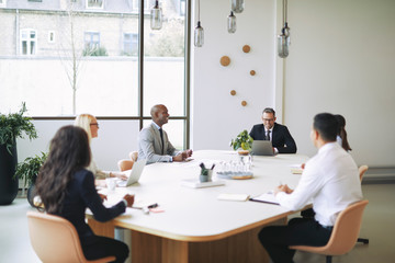 Diverse businesspeople sitting around a boardroom table discussi