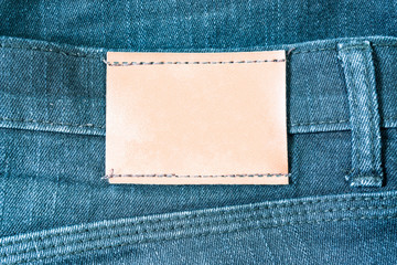 Leather label sewed on jeans. leather label on worn blue denim with orange seams, good for background.