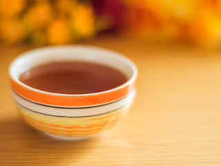 striped yellow orange bowl with black tea stands on a wooden table
