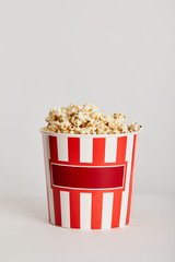 delicious popcorn in red striped paper bucket isolated on grey