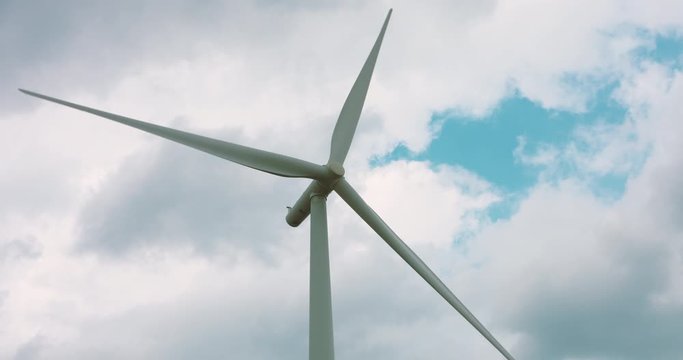 Wind turbine blades spinning against a cloudy background