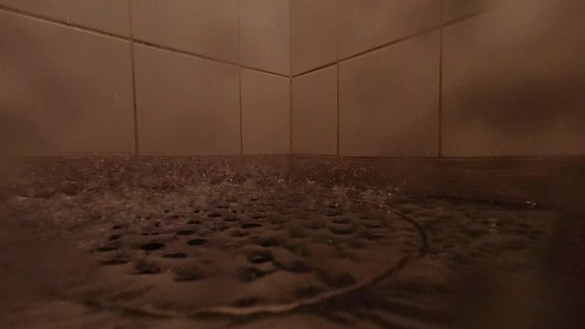 Shower drains. Flow of cold water falling in a bathroom floor. Drops in slow motion.