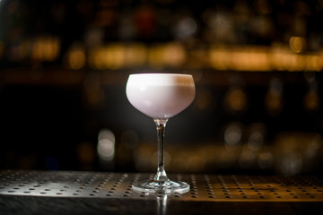 Glass with a delicious light violet color cocktail with a white scum