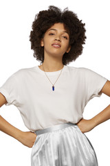 The medium front shot of a young mulatta lady with a golden chainlet with a pendant in the form of screw with a fitted-in indigo-blue gemstone similar to a lazulite on her neck.  © RedUmbrella&Donkey