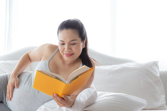Pregnancy and motherhood concept - Happy pregnant woman reading book on relaxing time. - Powered by Adobe