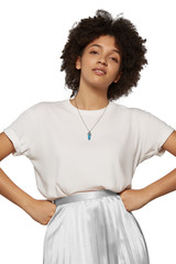 The medium front shot of a young lady with a steely chainlet with a pendant in the form of screw with a fitted-in blue gemstone similar to a turquoise with fibers.  © RedUmbrella&Donkey