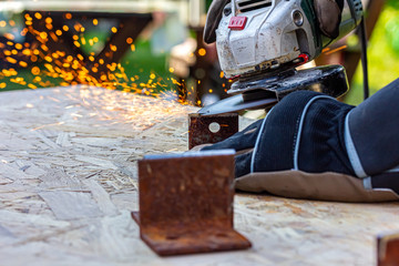 Metallteile werden mit elektrischem Schleifer bearbeitet, es fliegen Funken