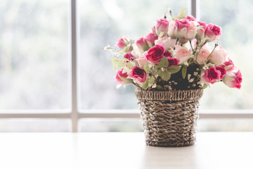 Flowers are in a wooden vase. Placed near the glass window on the wooden table in the room Giving a feeling of being in the spring.