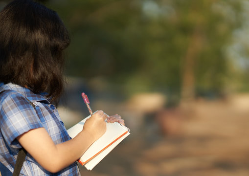 Girl notes in note book in natural field trip outside school