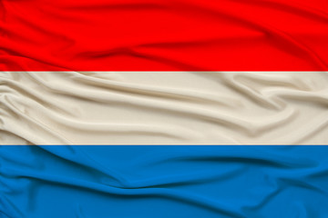 beautiful photo of the Luxembourg national flag on delicate shiny silk with soft draperies, the concept of state power, country life, horizontal, close-up, copy space