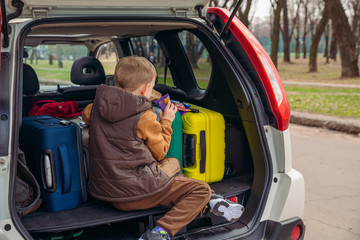Fototapeta na wymiar little kid looking into paper bag with candies sitting in car trunk