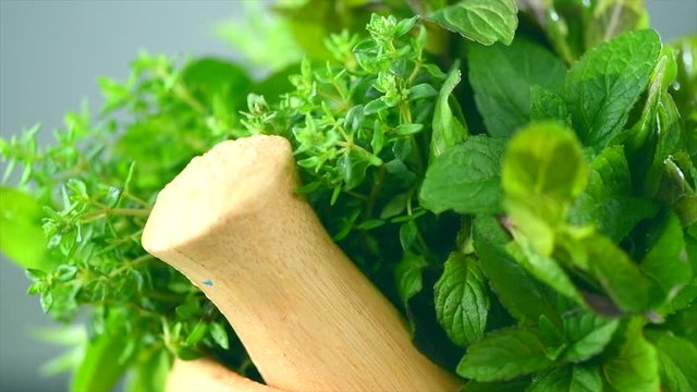 Herbs. Bunch of fresh green organic aromatic herb leaves in wooden mortar with pestle rotated. Mint, Peppermint, Rosemary, Thyme, Sage. 4K UHD video footage. 3840X2160